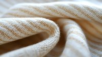 Soft cream knitted fabric with textured weave pattern draped elegantly, perfect for cozy home decor, fashion design projects and textile backgrounds.