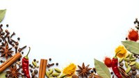 Aromatic spices and herbs border frame with cinnamon sticks, star anise, cardamom pods, bay leaves and colorful seasonings on white background for culinary designs.