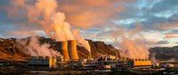 Geothermal power plant with steam rising from cooling towers against dramatic sunset sky in volcanic landscape for renewable energy concepts.