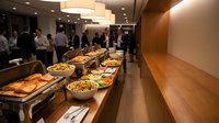 Corporate buffet catering setup in modern office space with diverse food selection for business lunch meeting or conference event.