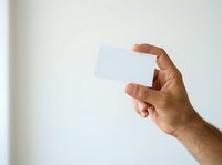 Male hand holding blank white card against neutral background, suitable for business branding, marketing mockups, and corporate identity presentations.