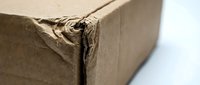 Damaged brown cardboard shipping box with torn corner and frayed edges showing wear from handling and transport for packaging design concepts.