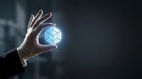 Hand holding glowing blue hexagonal geometric shape representing innovation, technology, and digital transformation in business and corporate environments.
