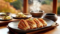 Sliced kimchi on ceramic plate with steaming traditional Korean side dishes served on wooden table against window view. Natural lighting enhances appetizing presentation.