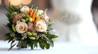 Fresh wedding bouquet with peach roses, green orchids, baby's breath and mixed foliage against soft blurred background, elegant floral arrangement for bridal ceremony.
