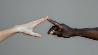 Two diverse hands reaching towards each other against gray background, symbolizing unity, connection and breaking racial barriers. Powerful metaphor for equality and humanity.