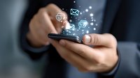 Hands holding smartphone with glowing message icons floating above screen, depicting digital communication and mobile messaging technology.