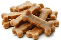 Pile of golden brown dog bone treats isolated on white background for pet food packaging and veterinary care marketing materials.