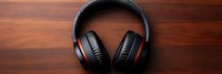 Black wireless headphones with red accents on wooden surface for music listening and audio entertainment technology concept.
