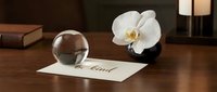 Be kind calligraphy card on wooden desk with crystal ball and white orchid flower, elegant mindfulness and wellness concept.