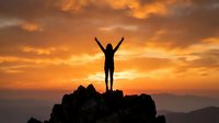 Woman silhouette with raised arms celebrating success on mountain peak during golden sunset sky. Achievement motivation concept for wellness goals.