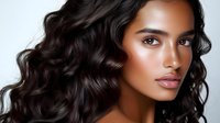 Young South Asian woman with glowing bronzed skin, dark wavy hair, and natural makeup in professional beauty portrait showing flawless complexion and modern glamour style.
