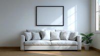 Modern white couch with soft pillows against plain wall with empty black frame and potted plant, minimalist scandinavian interior design for living room space.