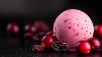 Pink ice cream scoop with fresh and dried cranberries scattered around on dark background with water drops, macro food photography for dessert menu or recipe blog.
