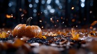 Orange pumpkin on dark background with autumn leaves and magical bokeh lights, creating mysterious Halloween atmosphere with flying sparkles.