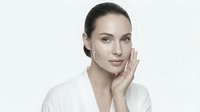 Young Caucasian woman with natural makeup touching face gently, skincare and beauty concept for cosmetic advertising and wellness campaigns.
