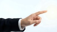 Professional businessman hand pointing finger gesture in formal black suit with white shirt cuff on clean background for business presentations and corporate communication.