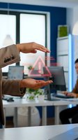 Businesswoman holding glowing warning alert symbol in modern office environment, representing cybersecurity risk, system failure, or data breach notification for corporate safety concepts.