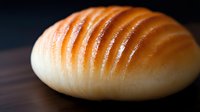 Fresh baked bread loaf with golden crust and diagonal scoring marks on wooden surface. Artisan bakery product for food photography and culinary content.