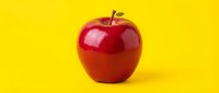 Red apple with glossy finish isolated on bright yellow background, suitable for food, health, nutrition, and wellness design projects.