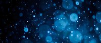 Abstract blue bokeh lights on dark background with sparkling particles and glowing orbs creating dreamy atmosphere for festive designs and celebrations.