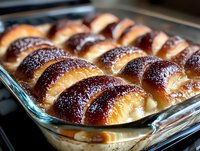 Freshly baked crescent rolls dusted with cinnamon sugar in a glass baking dish, perfect for bakery, food photography, and culinary content.