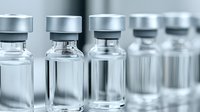 Medical glass vials with aluminum caps in row on light background, pharmaceutical ampoules containing vaccine or medicine, selective focus on front vial.