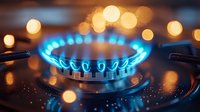 Gas stove burner with blue flames and warm bokeh lights creating cozy kitchen atmosphere for cooking and culinary concepts.