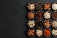 Wooden bowls filled with diverse superfoods, grains, nuts and spices arranged in geometric pattern on dark background. For healthy eating and cooking blogs.
