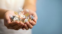 Real estate investment concept with hands holding miniature houses and percentage symbols representing mortgage rates and property returns.