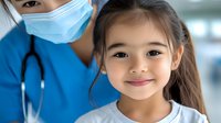 Young Asian girl smiling during medical checkup with pediatrician in blue scrubs and surgical mask. Healthcare and preventive medicine concept.