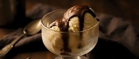 Vanilla ice cream scoops topped with chocolate sauce in a glass bowl, perfect for dessert menus, food blogs, and culinary content.