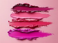 Vibrant pink and magenta cosmetic smears showing texture and layers of creamy makeup swatches against soft pink background, demonstrating lipstick or cream product consistency.
