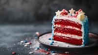 Patriotic red velvet layer cake slice with cream cheese frosting, decorated in red, white and blue colors on dark background with festive sprinkles and stars.