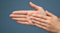 Two open hands positioned together showing palms and fingers in protective or offering gesture against neutral background for wellness concepts.