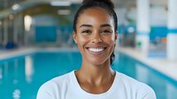 Young African American woman with bright smile wearing white t-shirt at indoor swimming pool, wellness and healthy lifestyle concept. Natural lighting and positive energy.