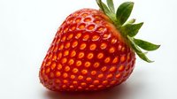 Fresh ripe strawberry with green leafy crown isolated on white background, suitable for food packaging, recipe blogs, and healthy eating designs.
