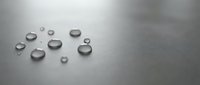 Water droplets on smooth gray surface creating minimalist composition for modern design projects and clean aesthetic backgrounds.