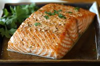 Grilled salmon fillet with herbs and spices on wooden board, cooked seafood dish ready to serve for healthy dinner meal.