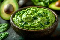 Fresh homemade guacamole dip with mashed avocado, cilantro and spices in rustic ceramic bowl, traditional Mexican appetizer on dark background.