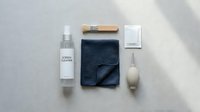Minimalist cleaning supplies flat lay with spray bottle, microfiber cloth, scrub brush and sponge on neutral background for household maintenance.