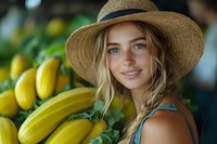 Young Caucasian woman in straw hat smiling near fresh yellow bananas at farmers market, natural lighting and soft bokeh background creates warm summer mood.