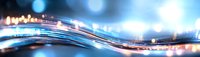 Abstract blurred motion background with flowing light trails and bokeh effects in blue and orange colors creating dynamic wave pattern for technology concepts.