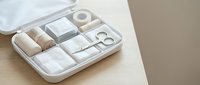 Organized white travel packing cubes with rolled clothes and accessories in suitcase for efficient luggage organization and minimalist travel preparation.