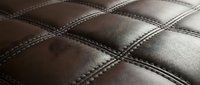 Brown leather upholstery with diamond quilted pattern and decorative stitching for luxury furniture and interior design applications.