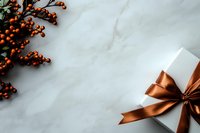 White gift box with copper satin bow and orange berry branches on marble background, festive flat lay composition with copy space for holiday design.