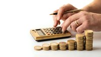 Business person calculating finances with golden coins stacked in ascending order and calculator on white background for budget planning concepts.