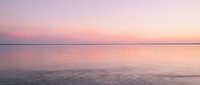 Serene dawn seascape with soft pink and purple hues reflecting across calm water, ideal for wellness, travel, and meditation content backgrounds.
