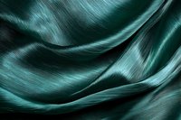 Luxurious emerald green silk fabric with soft waves and folds creating an elegant abstract pattern with subtle light and shadow play. Macro photography.