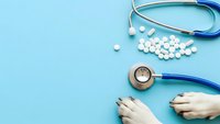 Medical stethoscope with white pills and hands on blue background for healthcare and medicine concepts.